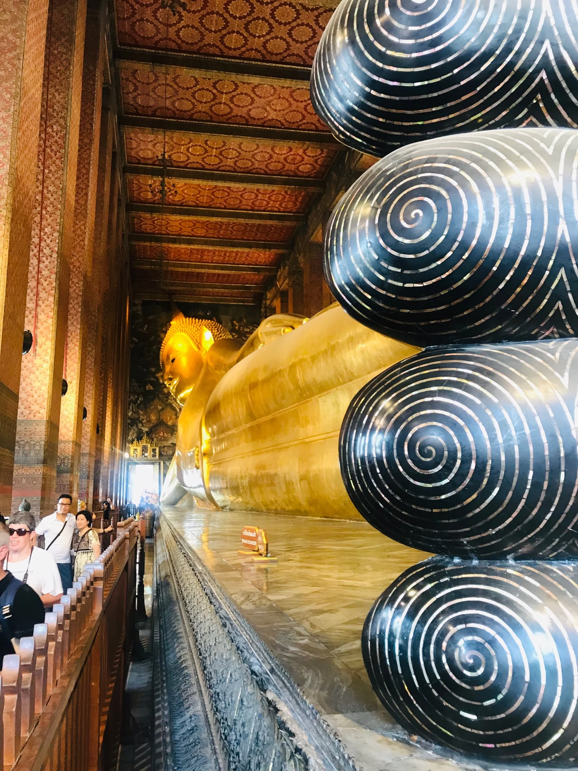 This is a very famous Buddha that is called the Reclining Buddha. In the front he is laying on a beautifully decorated cushion with very nice mosaics.